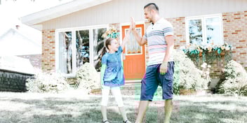 father and daughter high-fiving outside a house