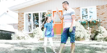 father and daughter high-fiving outside a house