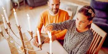 jewish dad and daughter lighting a menorah
