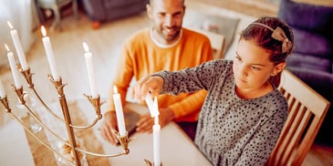 jewish dad and daughter lighting a menorah