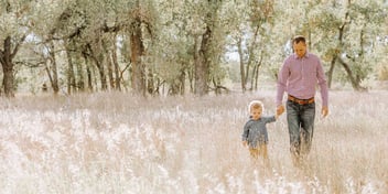 father and son walk in a field together