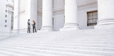 A couple of people talking outside of a courthouse