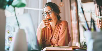 woman thinking while reading from laptop