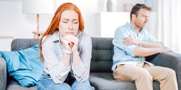 sad auburn haired woman sitting apart from her husband