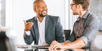 two men meeting in a formal office setting going over paperwork