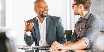 two men meeting in a formal office setting going over paperwork