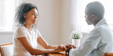 man and woman hold hands as they discuss their marriage