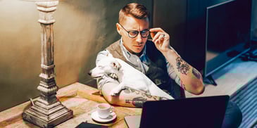 man holding his dog while looking at his computer late at night