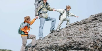 parent and children walking up a mountain together hand in hand