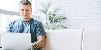 Young male sitting on couching working on laptop