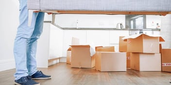 man lifts couch while moving out of his marital home filled with boxes