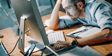 stressed and tired man staring at his computer monitor
