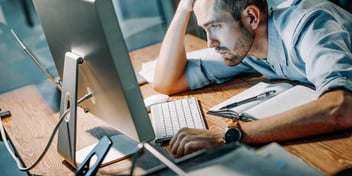 stressed and tired man staring at his computer monitor