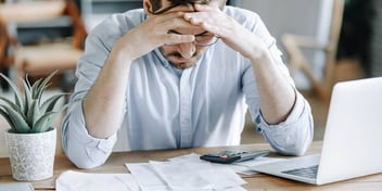 Man at computer with head in hands looking frustrated