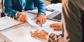 A man pointing at a document for his female client to review