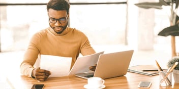 man reviewing paperwork regarding his finances at a work desk