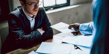 man sitting at a desk as he is served with divorce papers