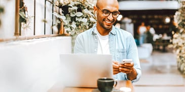 man smiling and looking at his phone at a cafe