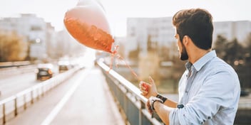 man standing on a bridge with a heart shaped balloon