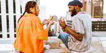 man and woman smiling talking and eating lunch together in a city