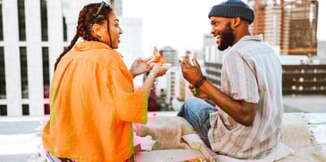 man and woman smiling talking and eating lunch together in a city