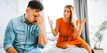 couple sitting on a bed and arguing