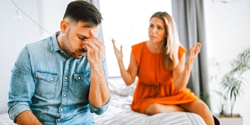 couple sitting on a bed and arguing