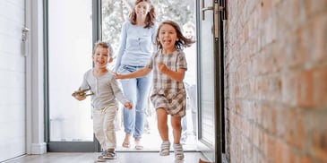 smiling mom and her son and daughter happy to arrive home