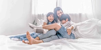 mom talking to her kids about divorce while relaxing together in bed
