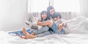 mom talking to her kids about divorce while relaxing together in bed