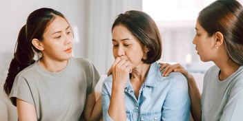 teenage daughters comforting their mother