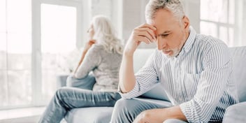 older unhappy couple sitting apart on sofa