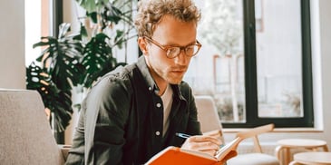 Man in glasses reading and taking notes