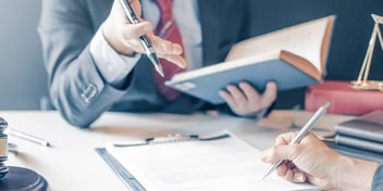 lawyer and client read over legal terms and fill out paperwork