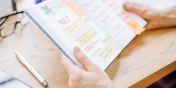 person looking at a weekly calendar in their planner