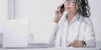 professional woman in an office talking on her phone at her desk