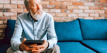 stressed out older man sitting on a couch against a brick wall
