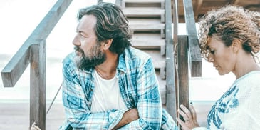 man and woman having a serious conversation by a staircase