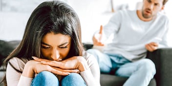 frightened woman cowering near her angry husband