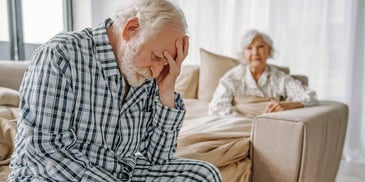 a couple of seniors looking sad after a fight in their bedroom
