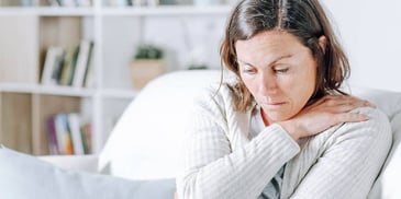woman holding her tense shoulders in pain 