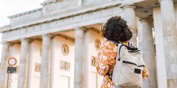 foreign traveler with backpack standing outside a historic building