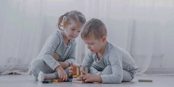A little boy and girl playing on the floor together building blocks