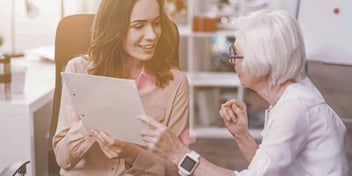 woman shows an older woman paperwork for changing her last name