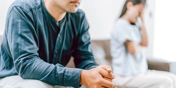 unhappy couple sitting apart on their couch and not speaking