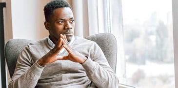 pensive Black man looking out a window