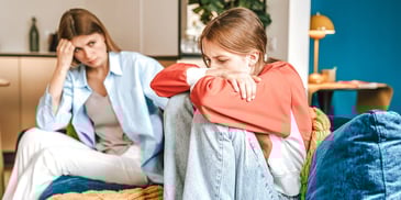 unhappy mother looking at her pouting preteen daughter