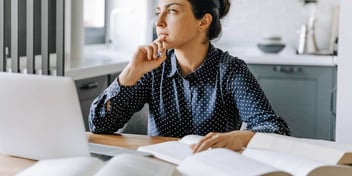 Woman looks out window while on a computer