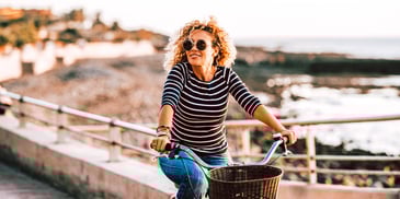 happy single woman riding a bike by the ocean