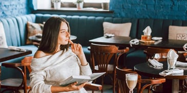 woman reading a book and drinking a cappuccino